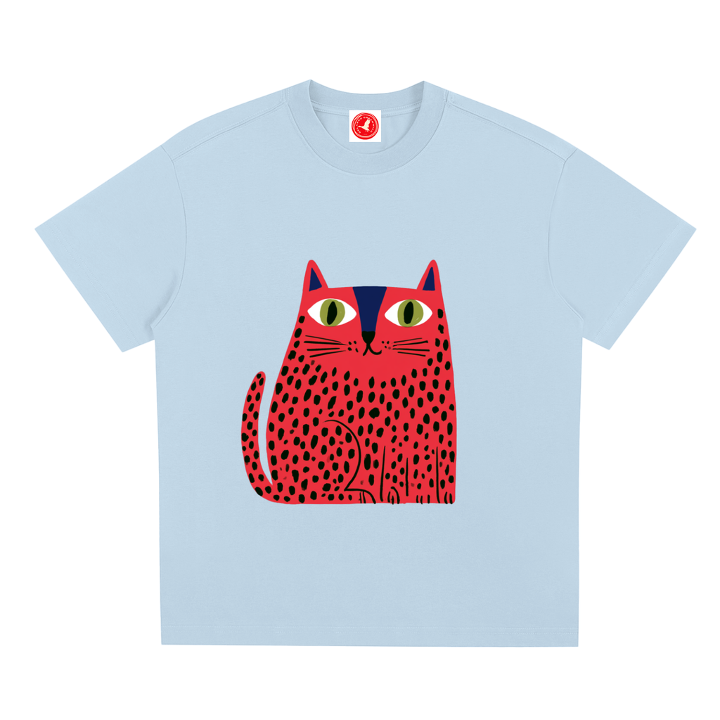 Light blue pink short-sleeve crewneck t-shirt featuring a stylized graphic of a red cat with black spots and green eyes on the front, displayed against a solid white background.