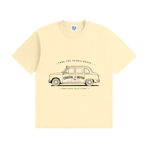 A pale cream-colored short-sleeve t-shirt with a vintage-style graphic of a classic London taxi on the front. The graphic features the text 'TAKE THE SCENIC ROUTE' above the taxi, which has 'COASTAL DRIFTER' written on its side, and 'EVERY PLACE TELLS A STORY' below it.