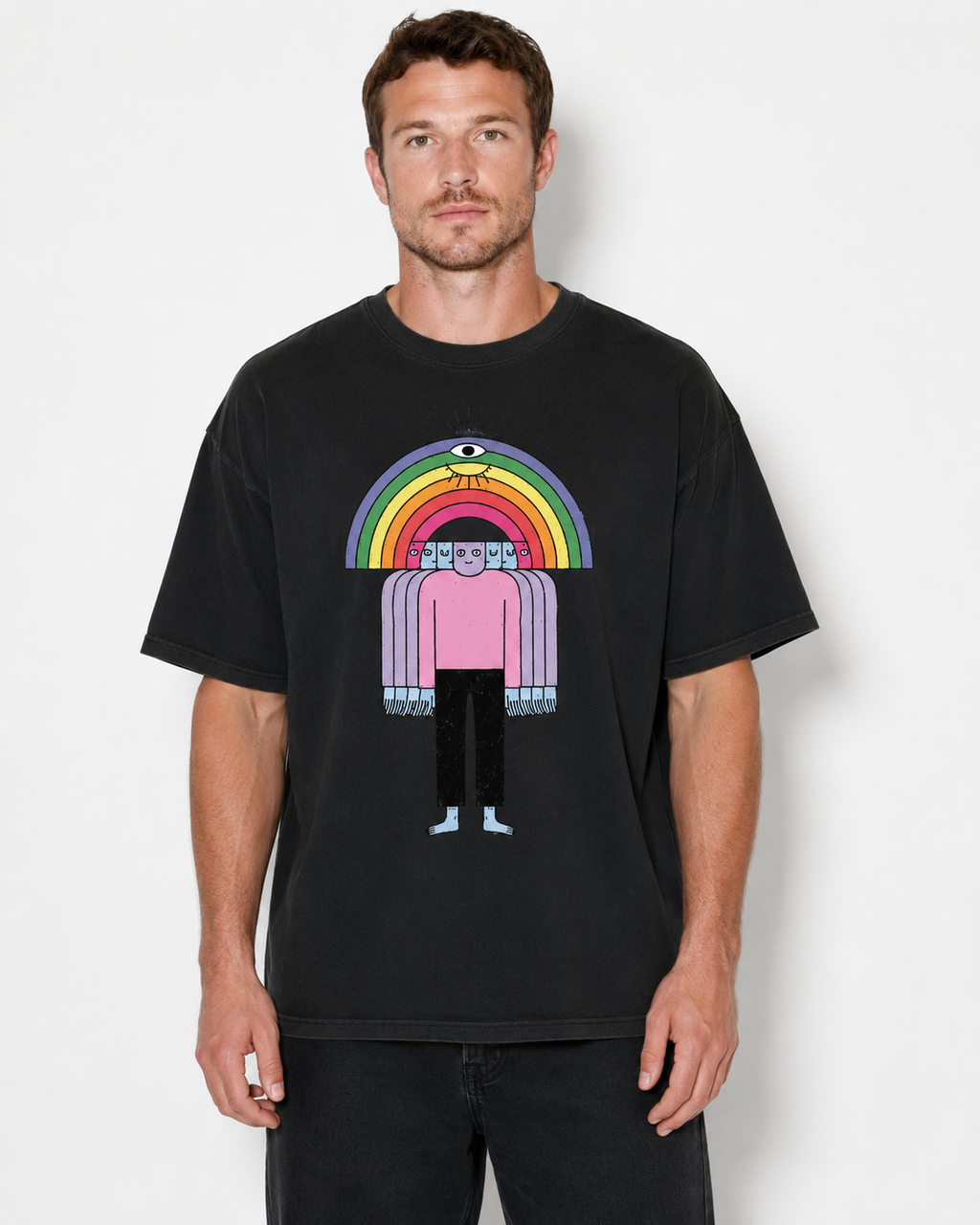 A man wearing a black graphic t-shirt featuring a stylized figure under a rainbow with an eye motif, set against a plain light gray background.