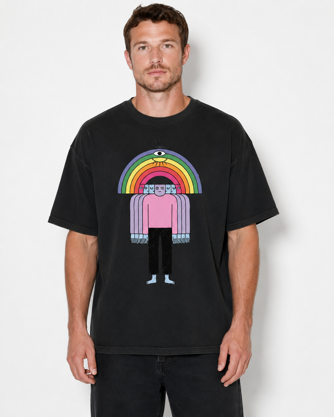 A man wearing a black graphic t-shirt featuring a stylized figure under a rainbow with an eye motif, set against a plain light gray background.