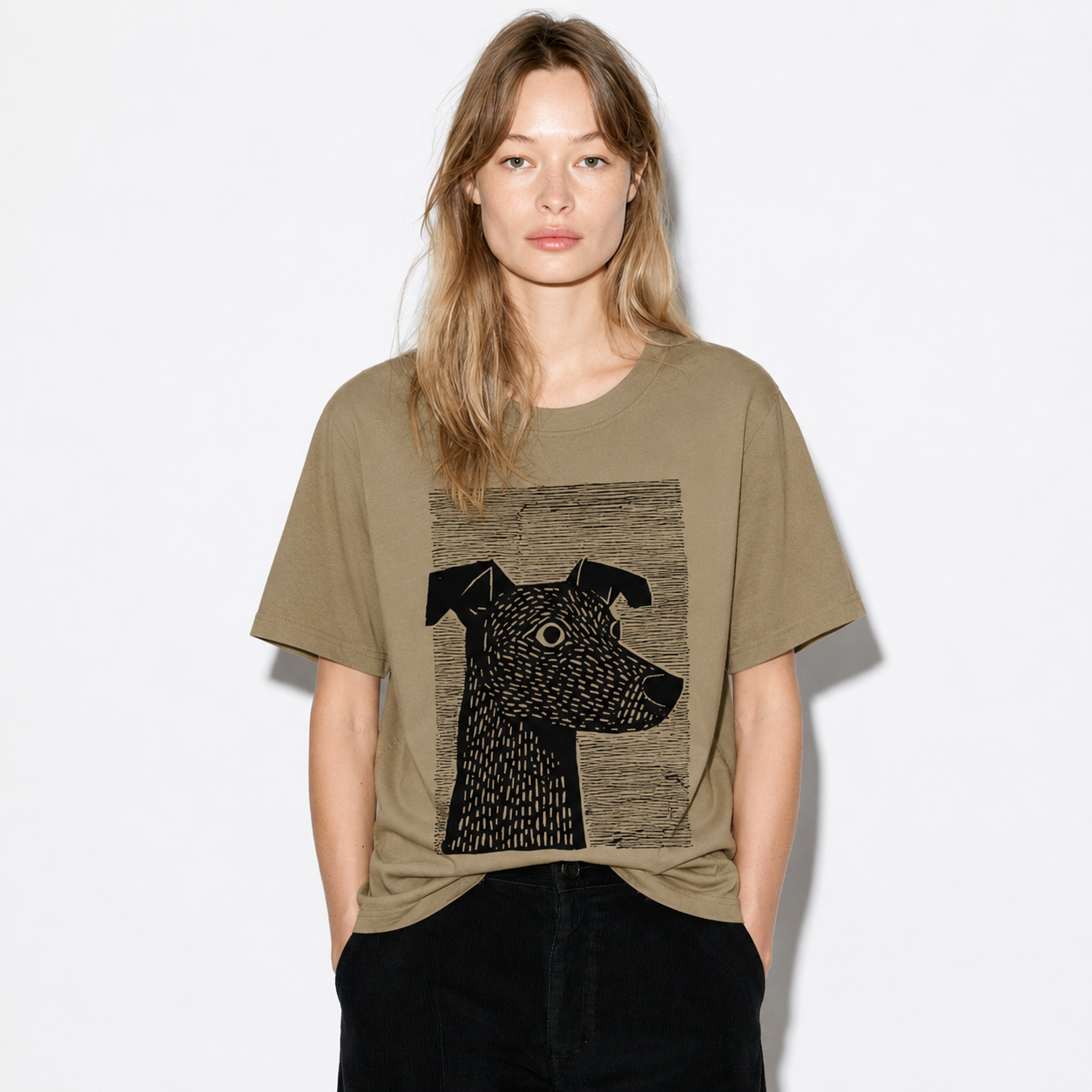 A woman modeling an oversized olive green t-shirt with a black graphic print of a dog's head, paired with black pants, against a plain white background.