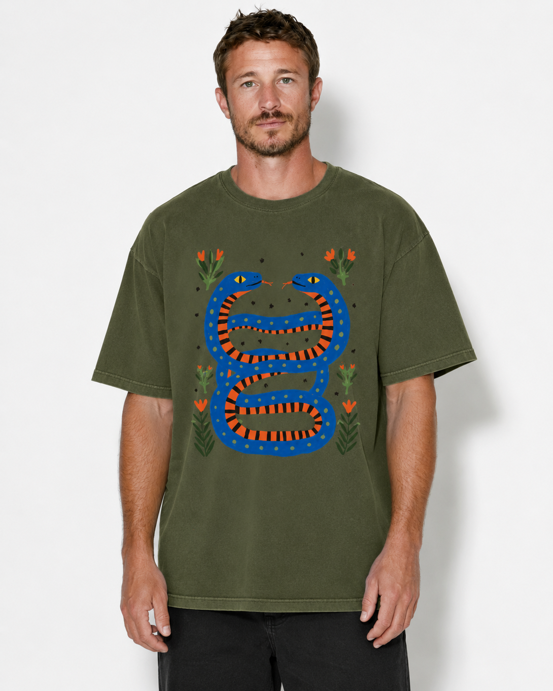 A man wearing an olive green t-shirt with a colorful graphic of a blue and orange snake wrapped around a tree trunk, surrounded by small orange flowers, against a light gray background.