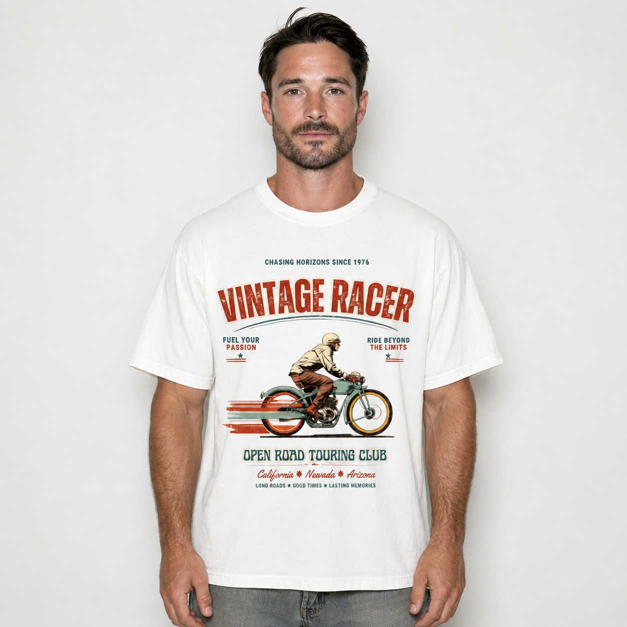 A man wearing a white graphic t-shirt with a vintage road racing design. The graphic features the text 'VINTAGE RACER' in red and black, along with an illustration of a motorcycle racer and the text 'OPEN ROAD TOURING CLUB'.