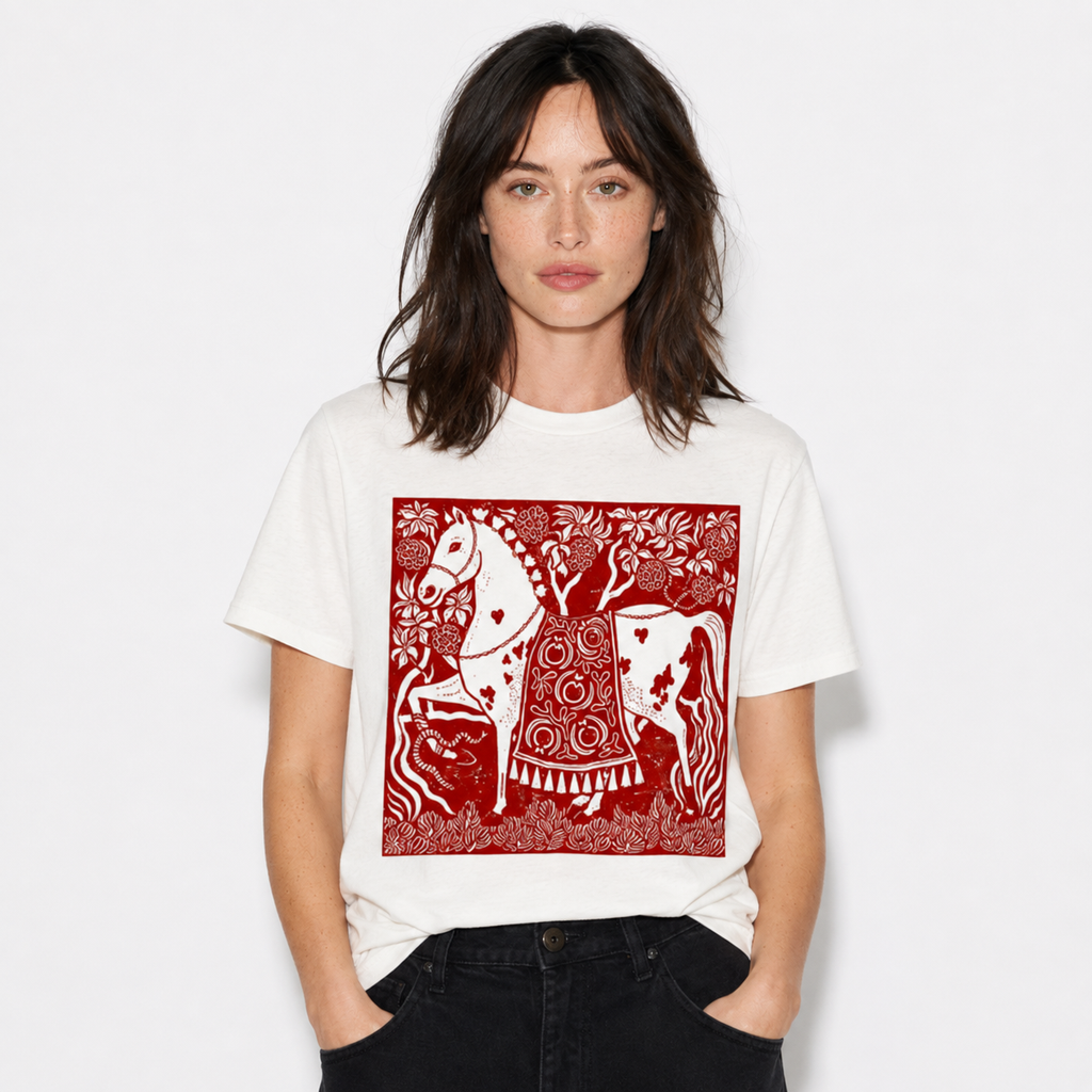 A woman wearing a white short-sleeve crewneck t-shirt with a large red graphic print of a stylized horse and rider, paired with black jeans, against a plain white background.