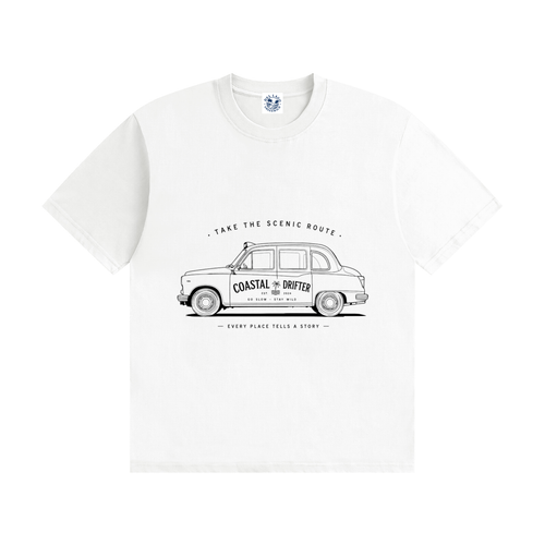A white short-sleeve crewneck t-shirt featuring a black line-art graphic of a classic London taxi with the words 'COASTAL DRIFTER' and 'TAKE THE SCENIC ROUTE' printed on the front.