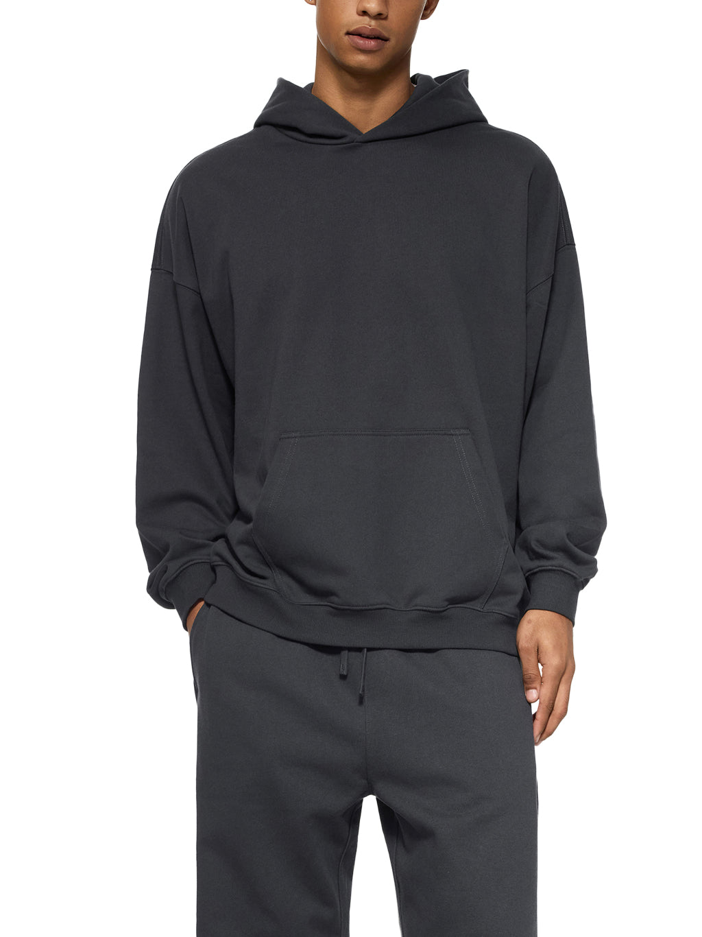 Person wearing a dark gray hoodie and pants on a white background