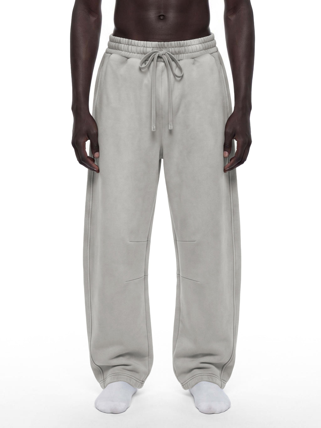 A model wearing light gray drawstring sweatpants, shown from the waist down against a plain white background.